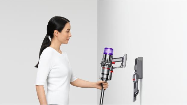 A person returns their Dyson V9 vacuum to their Wall dock.
