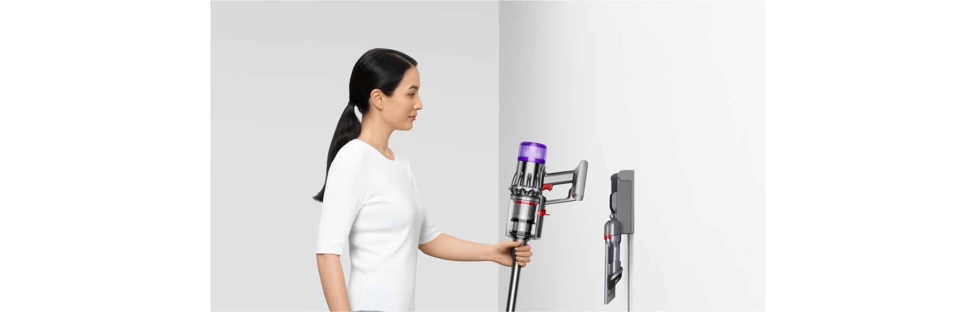 A person returns their Dyson V9 vacuum to their Wall dock.