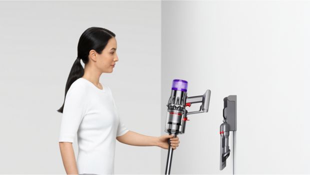 A person returns their Dyson V9 vacuum to their Wall dock.