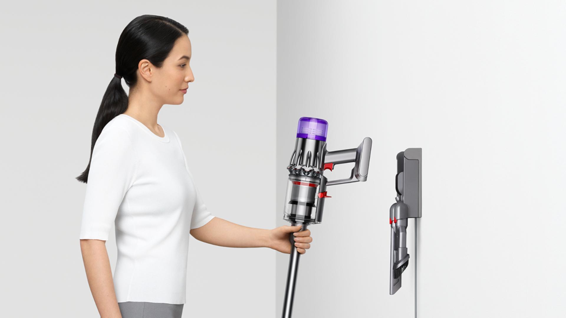 A person returns their Dyson V9 vacuum to their Wall dock.