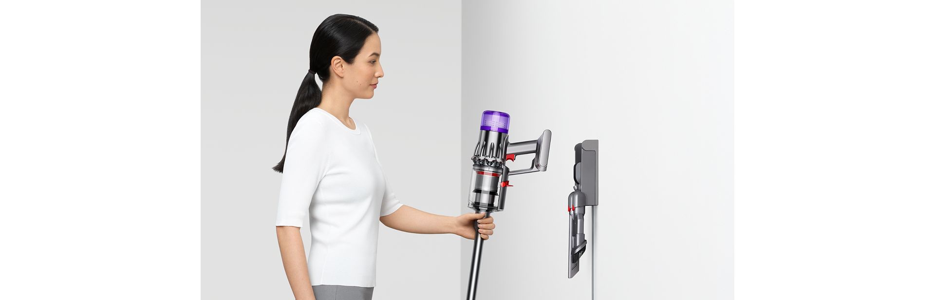A person returns their Dyson V9 vacuum to their Wall dock.