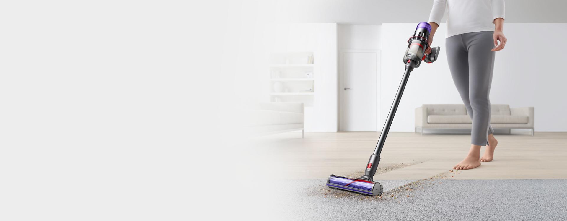 A person uses the Dyson V9 vacuum to clean hard floors and carpet in a home with the Motorbar cleaner head.