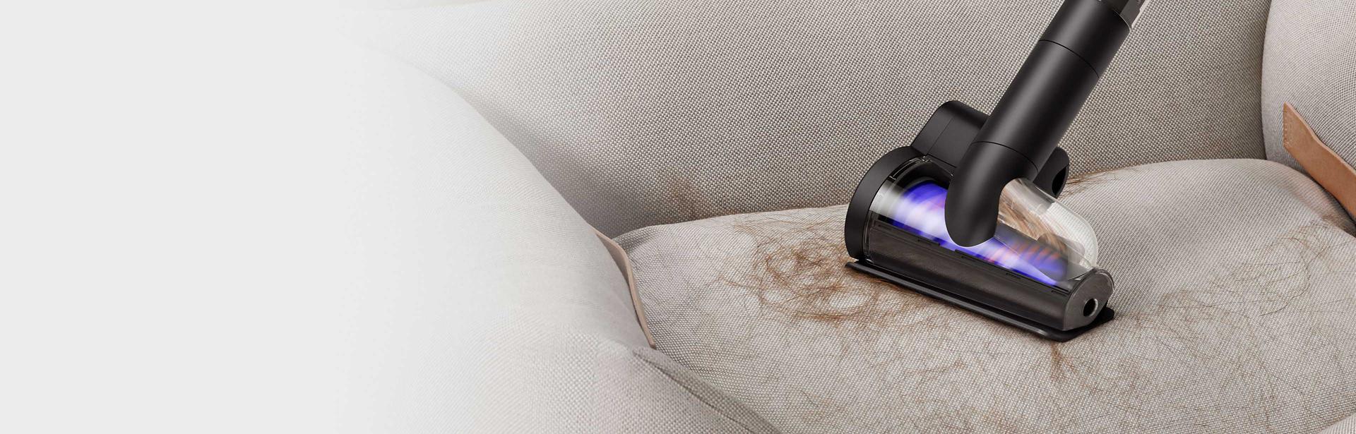 The Dyson PencilVac cleaner's Hair screw tool being used to pick up hair from furniture