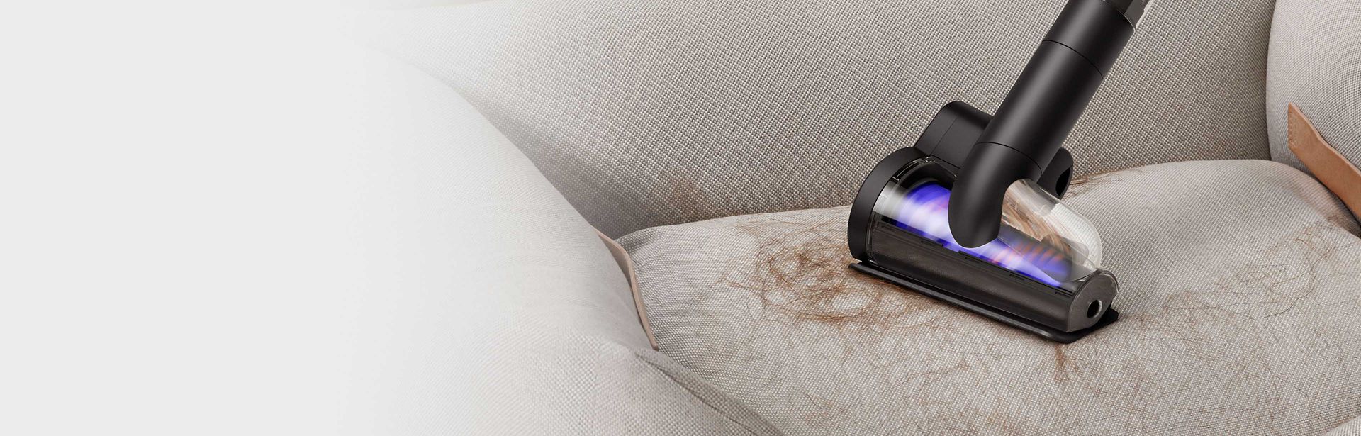 The Dyson PencilVac cleaner's Hair screw tool being used to pick up hair from furniture