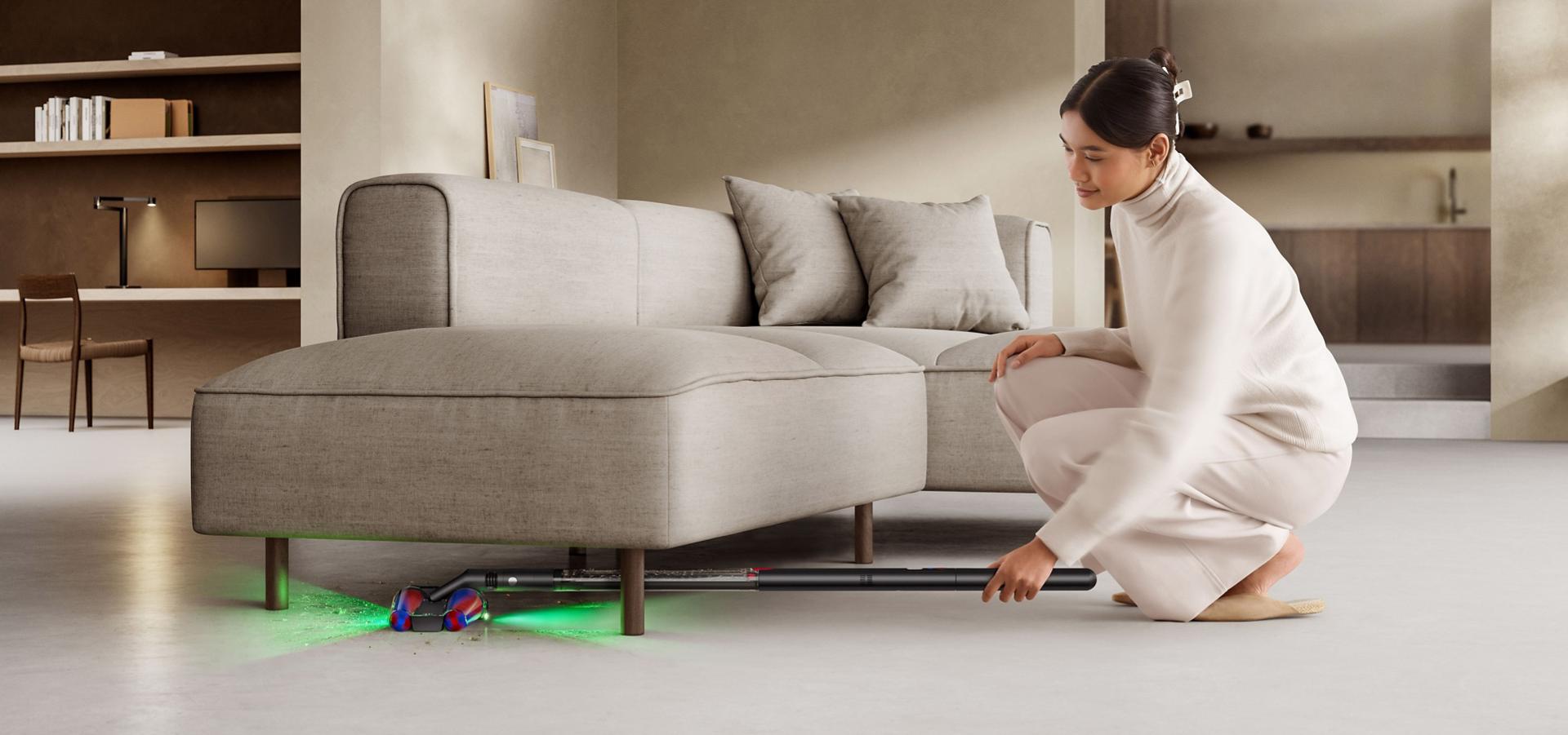 다이슨 PencilVac™ 펜슬백 청소기로 소파 아래를 청소하는 모습