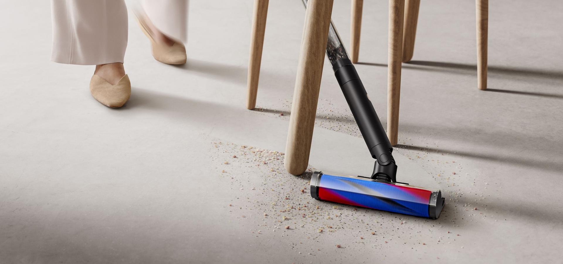 다이슨 PencilVac™ 펜슬백 청소기로 테이블 아래를 청소하는 모습