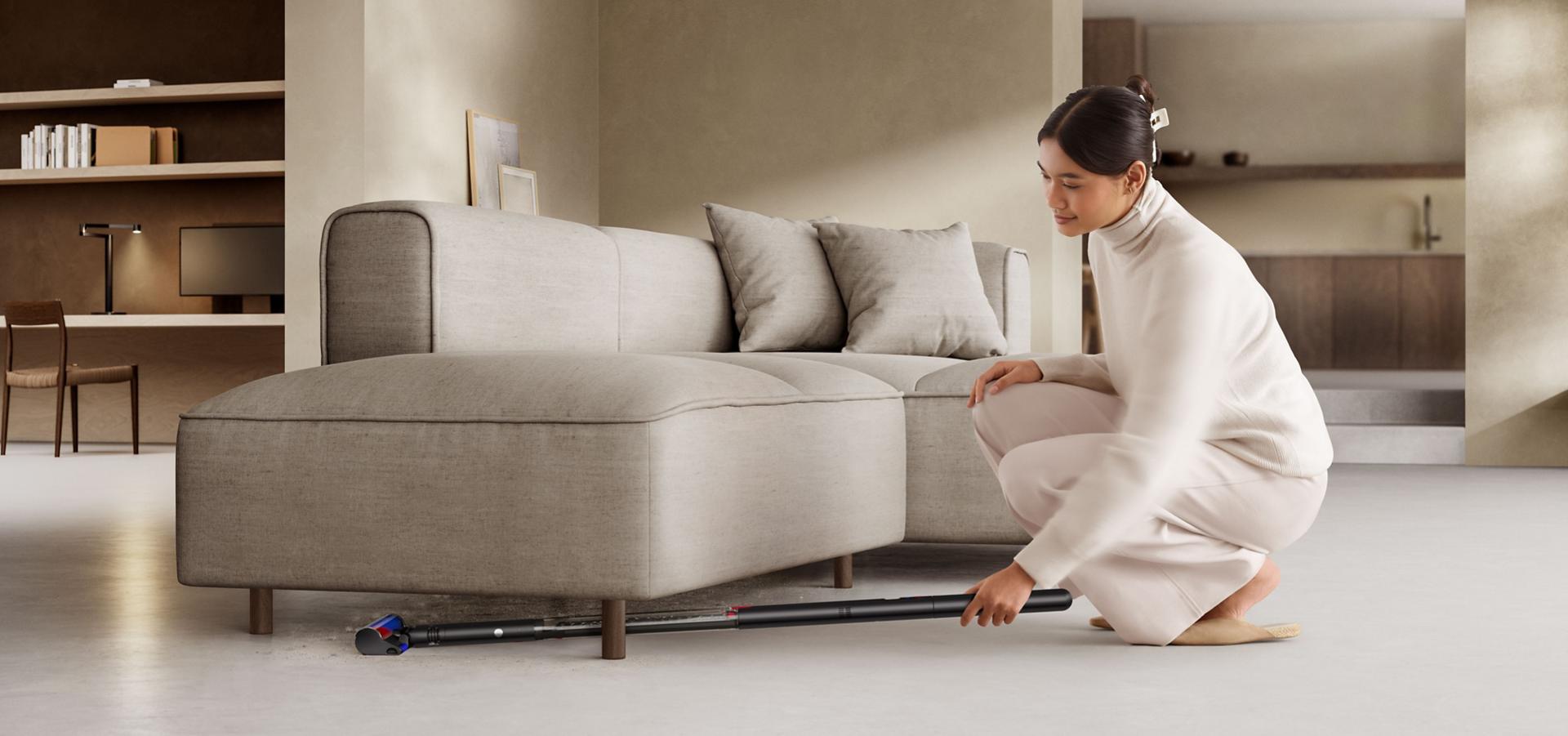 다이슨 PencilVac™ 펜슬백 청소기로 소파 아래를 청소하는 모습