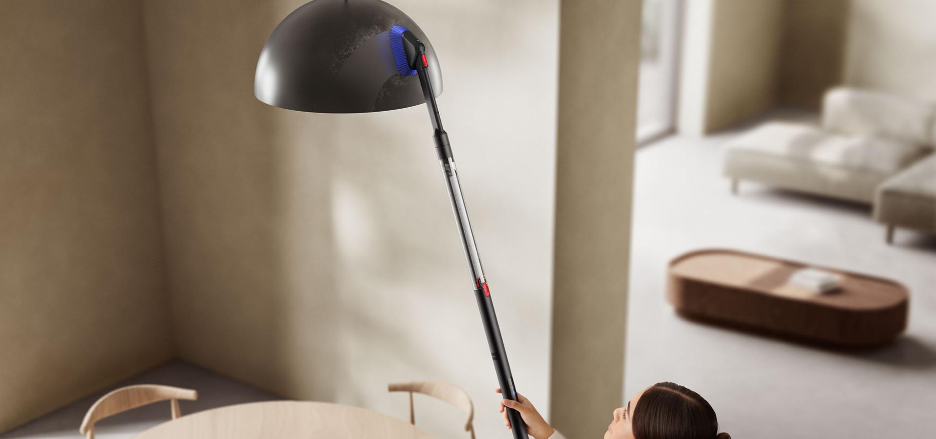 다이슨 PencilVac™ 펜슬백 청소기로 높은 곳의 조명 기구를 청소하는 모습