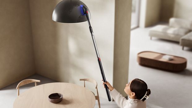 The Dyson PencilVac cleaner being used with the Combi crevice tool to clean a lightshade high up