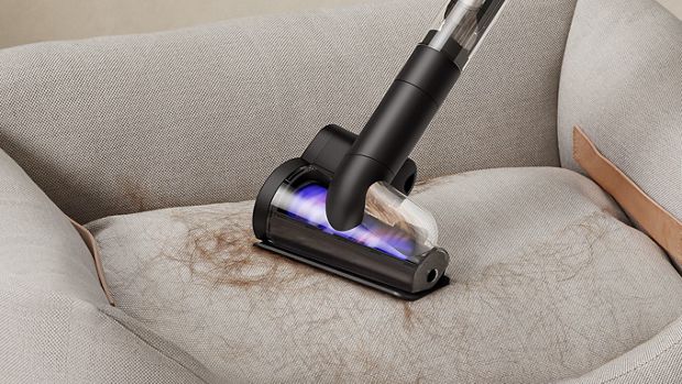 The Dyson PencilVac cleaner being used with the Hair screw tool to remove pet hair from a pet bed