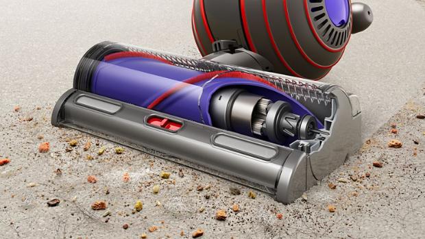 A Dyson Upright vacuum cleaner with the Motorbar cleaner head removes built up debris from a carpet.