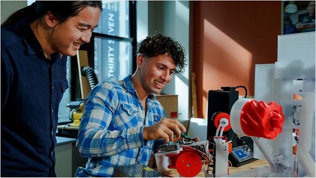 Young engineers in discussion while one holds a Dyson cyclone.