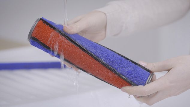 Soft roller being washed under a tap