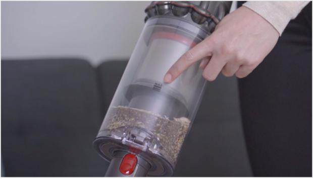 O femeie arătând semnul MAX pe recipientul de praf Dyson V11™