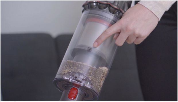 O femeie arătând semnul MAX pe recipientul de praf Dyson V11™