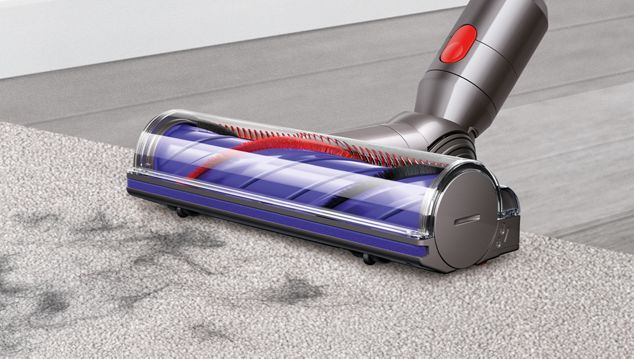Kvinna rengör golv med Dyson cyklon V10-dammsugare 