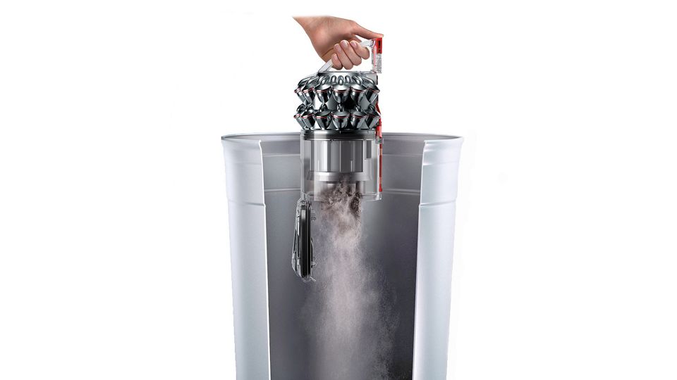 Person emptying a Dyson DC46 canister vacuum bin into a household bin