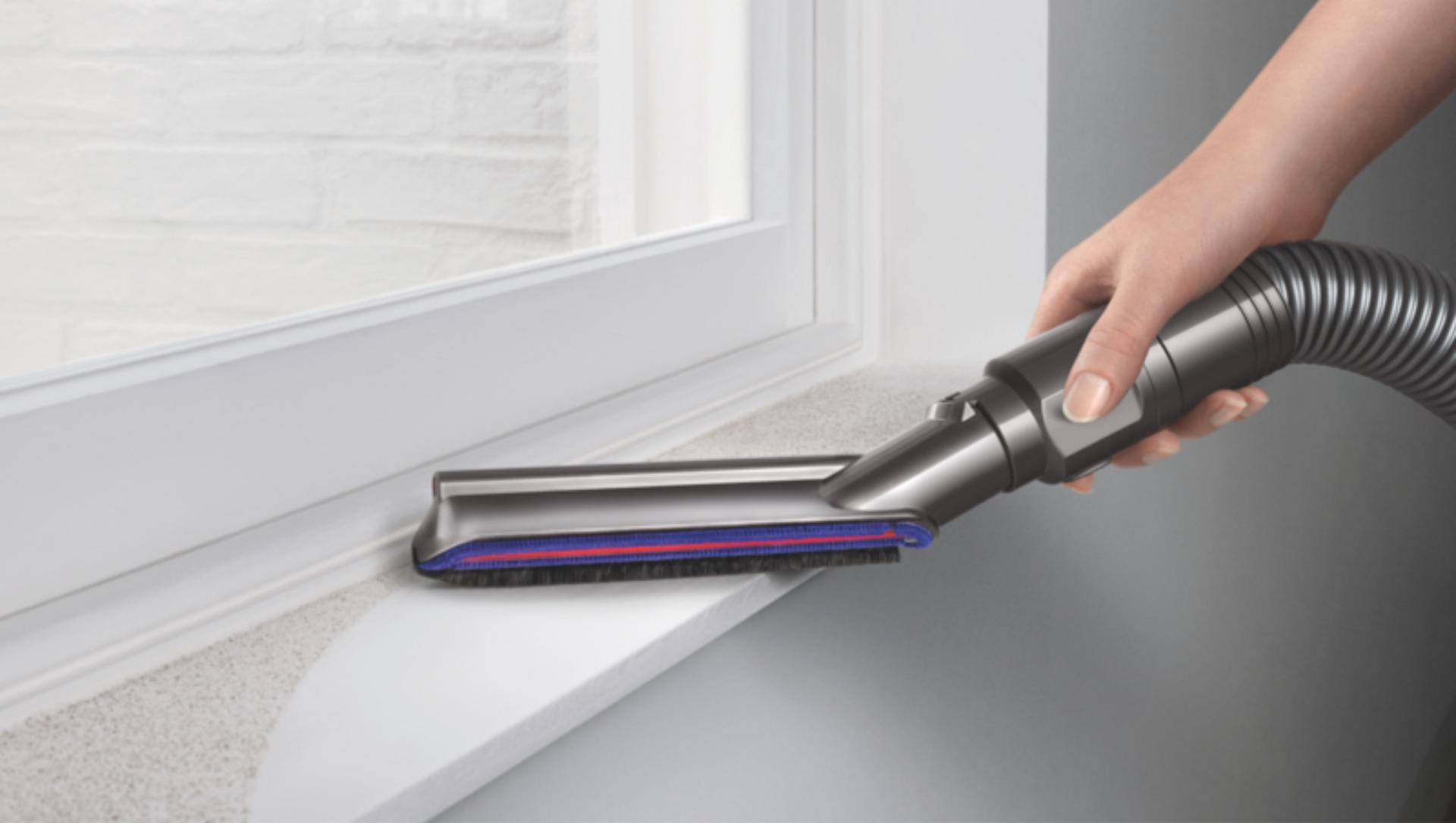 Vacuum cleaner head picking up debris from four different intersecting floor types.