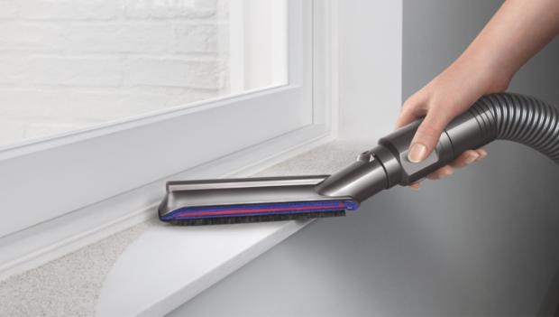 Vacuum cleaner head picking up debris from four different intersecting floor types.