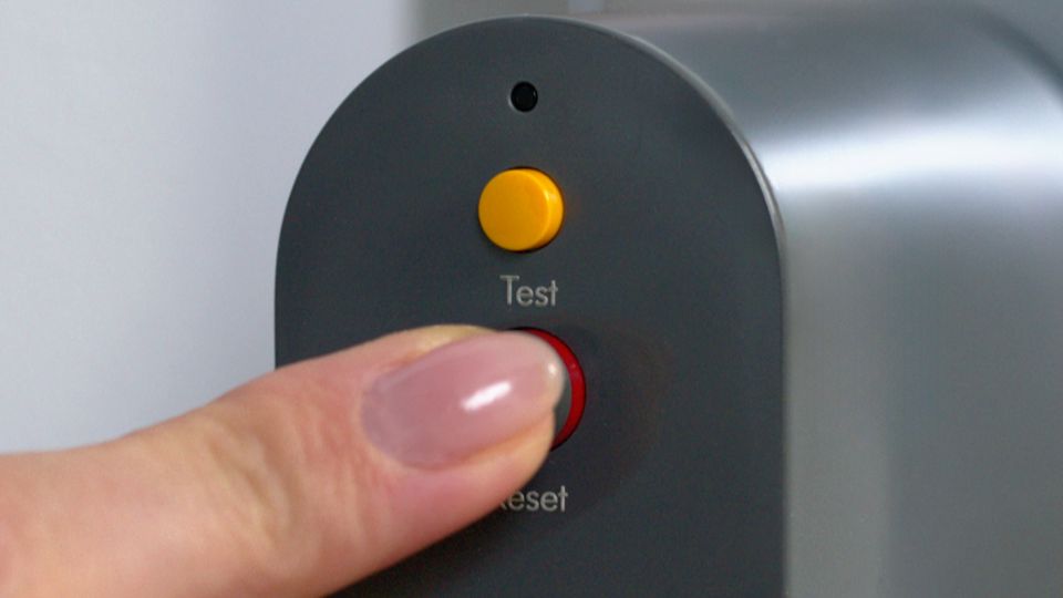 A user's finger pressing the RESET button on the PRCD 