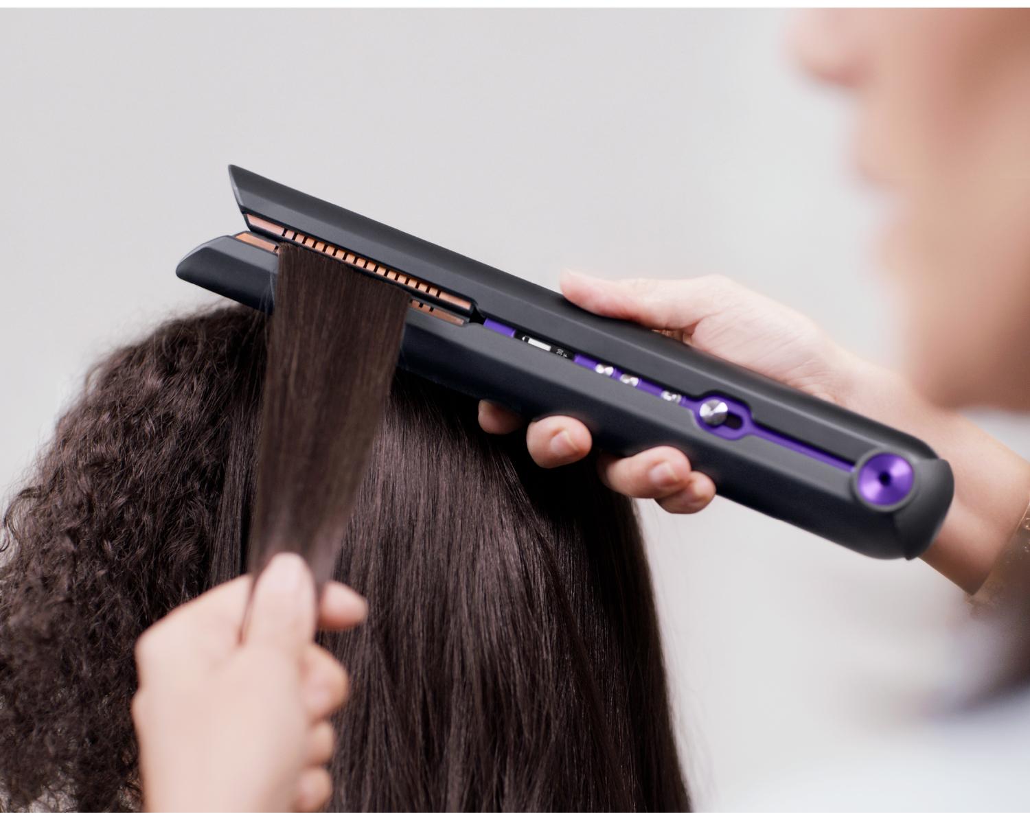Stylist gathering client's hair in straightener's flexing plates