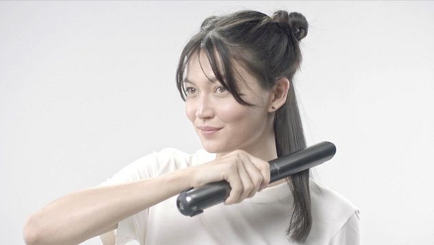 Woman straightening her hair 