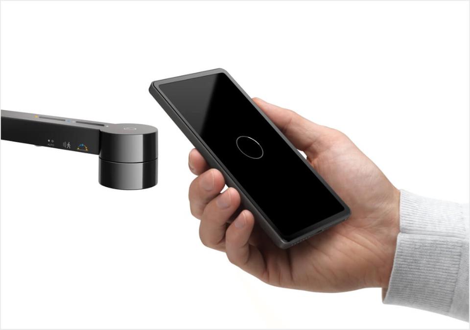 En person holder smarttelefonen sin nær lampen for å koble seg til