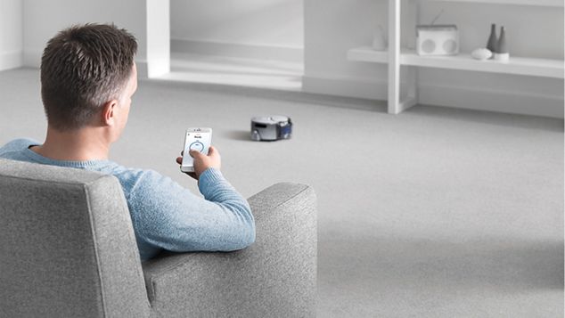 Bildet viser en mann som styrer Dyson 360 Eye med Dyson Link-appen.