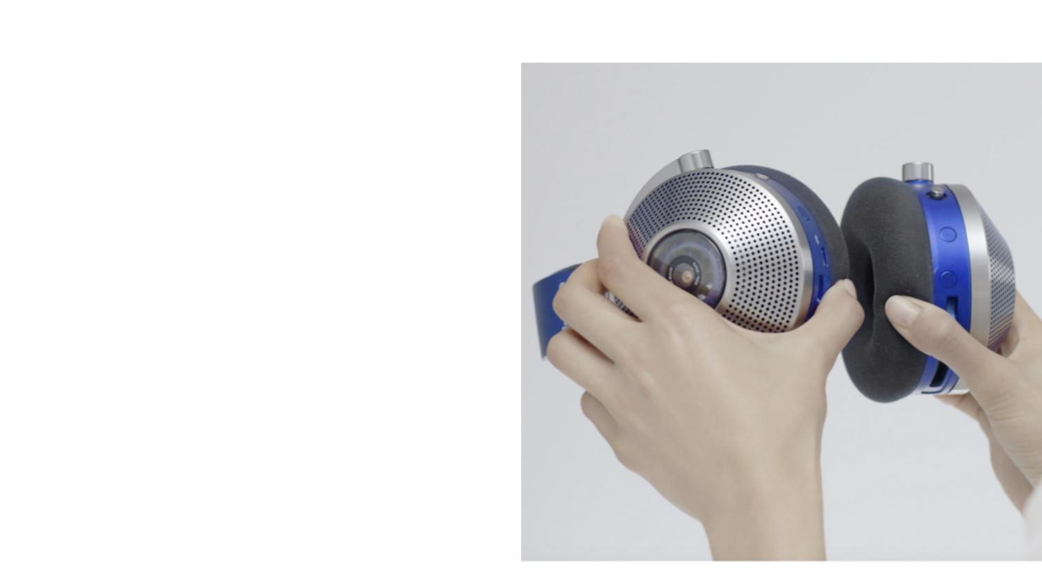Hands holding the ear cups of the Dyson Zone headphones.