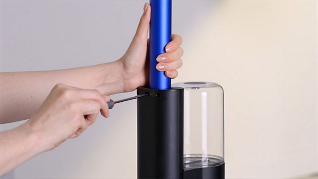 A user rinsing the red inner section uner a runing tap