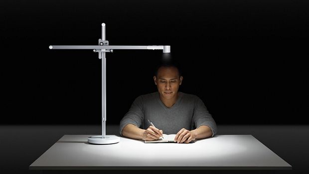 Un hombre trabajando bajo una potente luz de escritorio