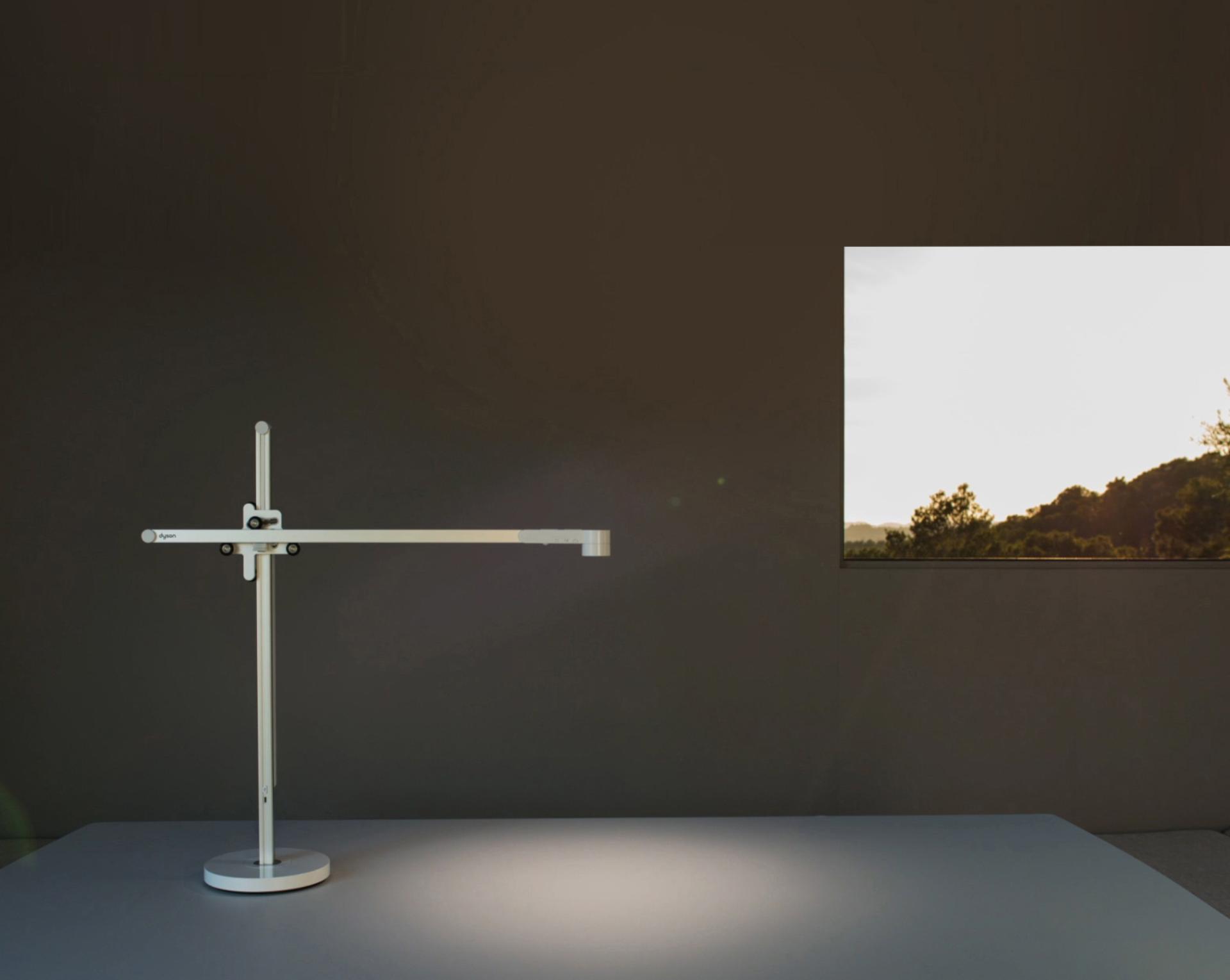 La lámpara de trabajo Dyson Lightcycle se ajusta con la luz solar afuera de una ventana