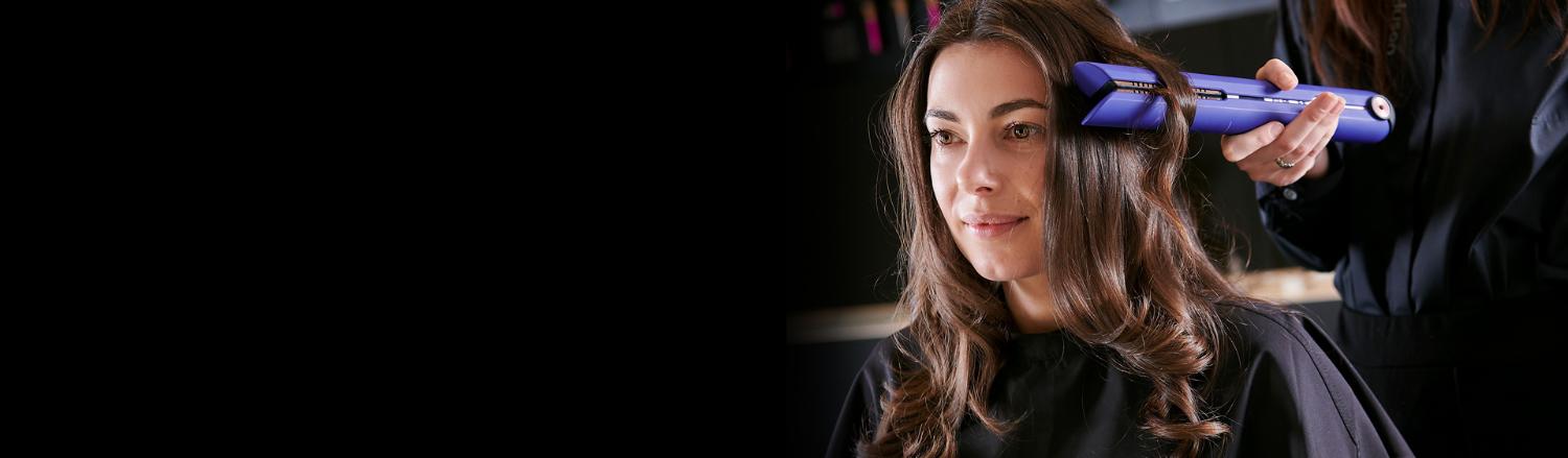 Vrouw krijgt een stylingsessie met de Dyson Corrale stijltang in Vinca blauw en Rosé