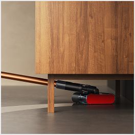 The Dyson PencilWash cleaner is used to clean underneath a low cabinet.
