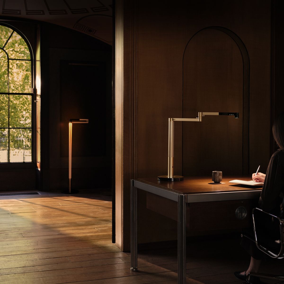 A Dyson solarcycle morph lamp illuminates a desk and appears in the distance