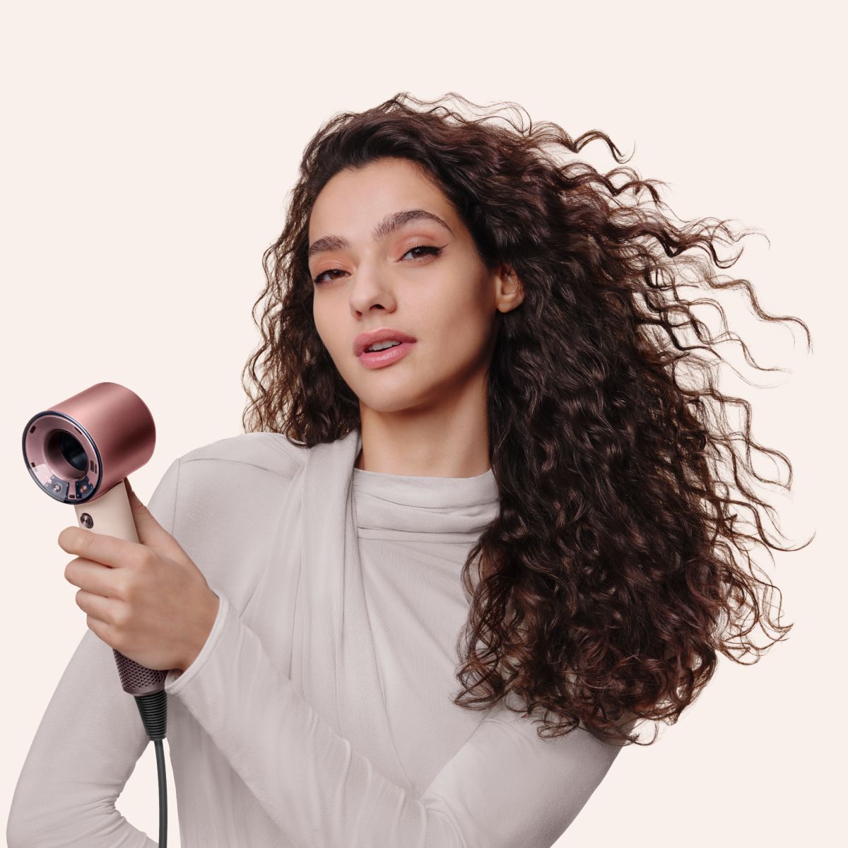 Model with curly hair uses the Dyson Supersonic Travel hair dryer to dry her hair.