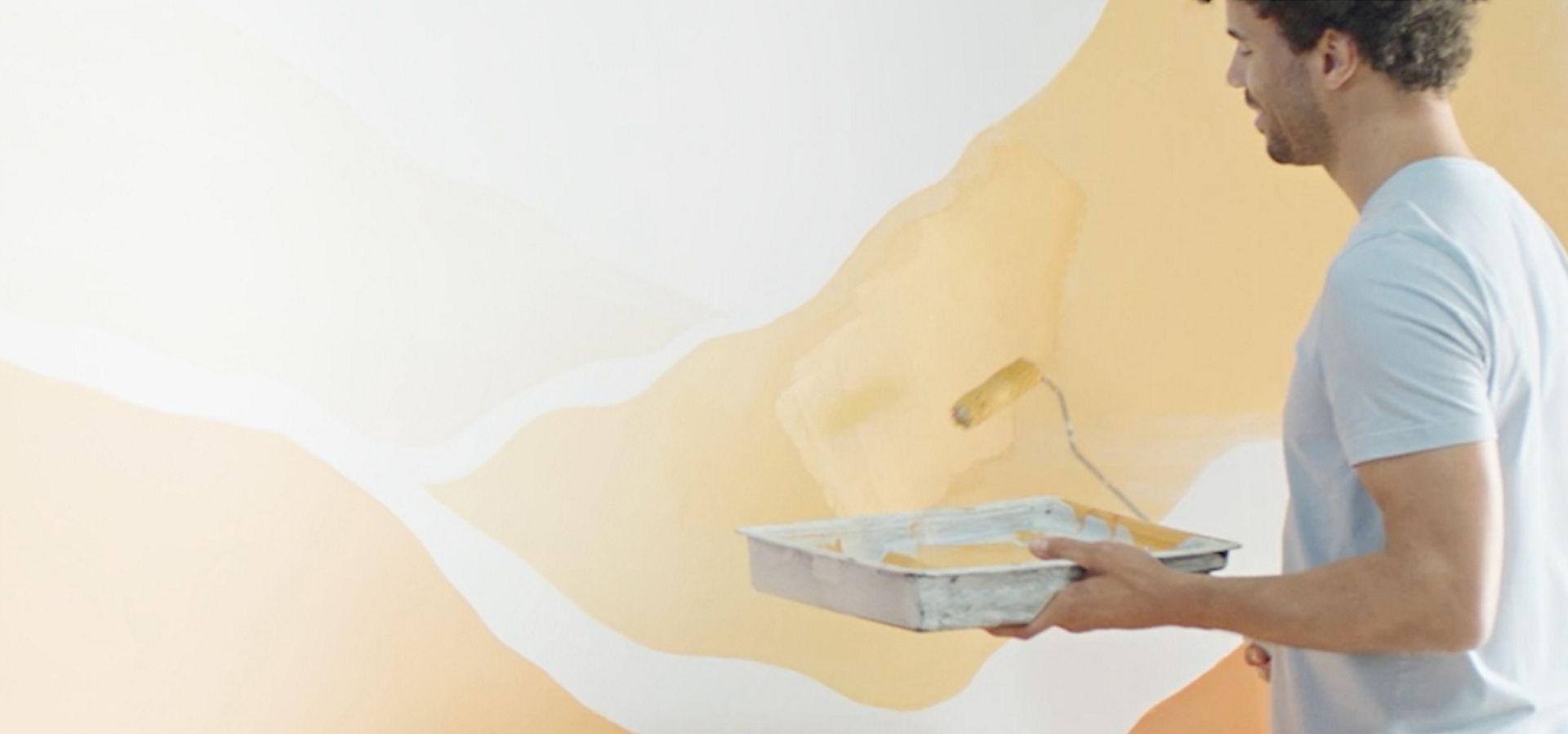 A man with paint roller, decorating interior wall.