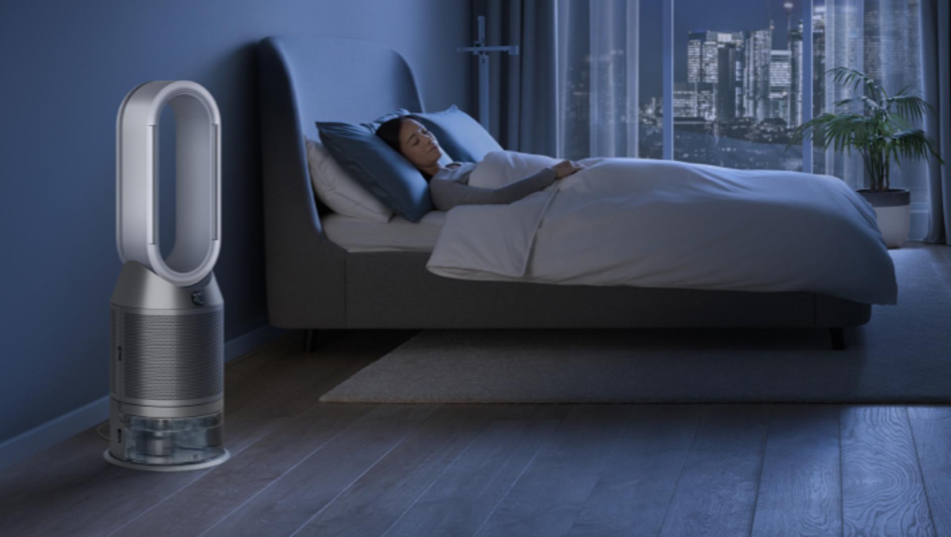 Mujer en cama al lado de un purificador y humidificador Dyson