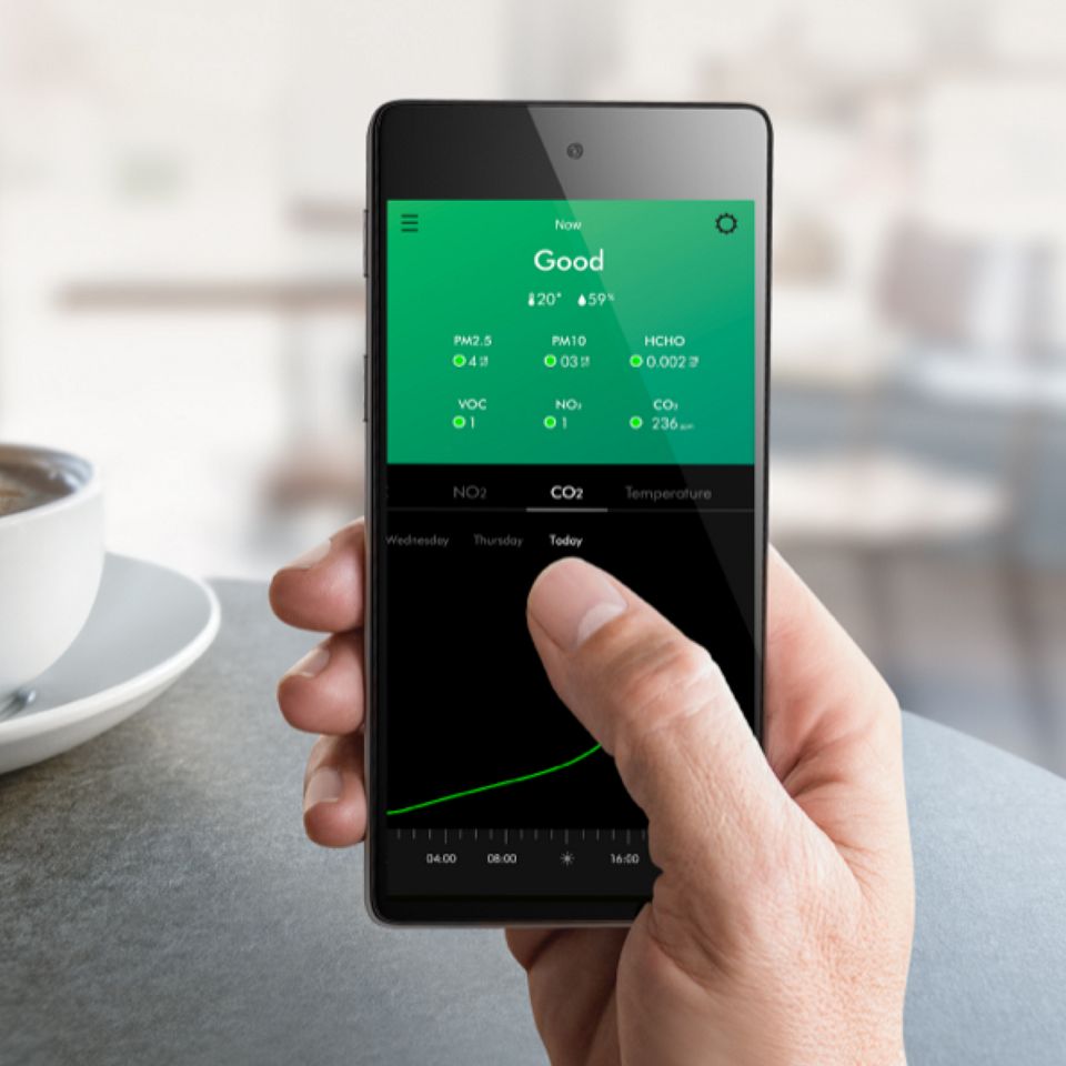 Eine Hand hält ein Mobilgerät, auf dem der Startbildschirm der App angezeigt wird.