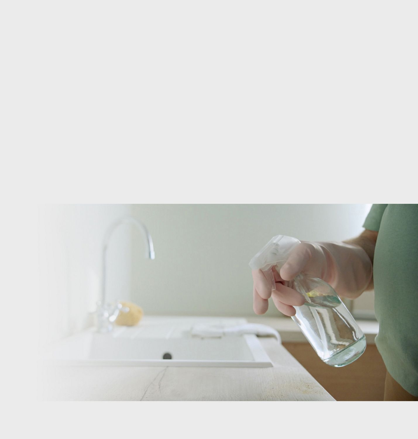 Cleaning the surfaces by a kitchen sink. A person using a cleaning product on a surface.