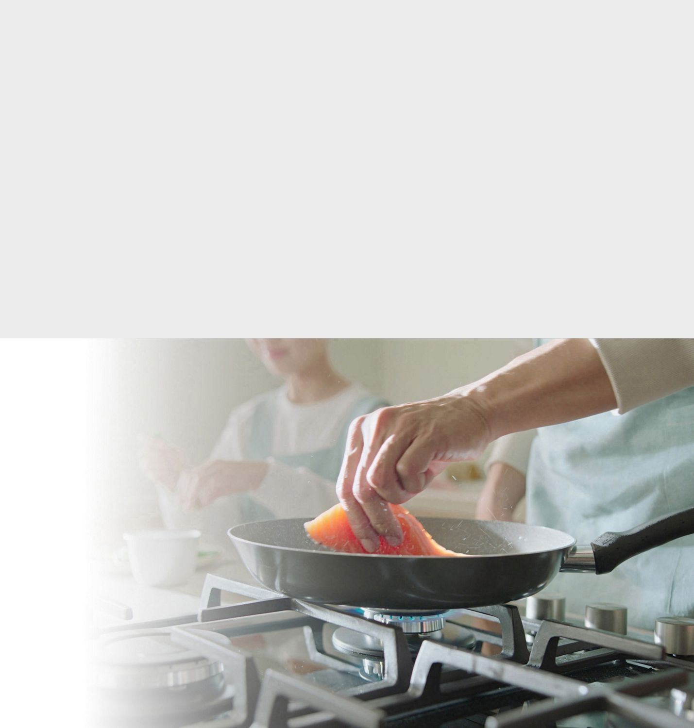 Fish being fried in a frying pan. Food being cooked on a gas top stove.