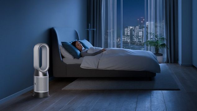 A Dyson purifier purifying a room at night next to a bed