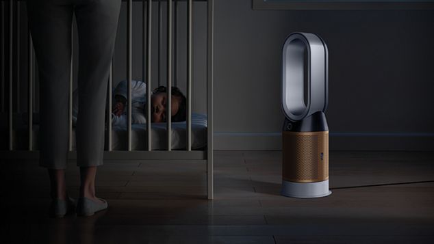  A baby sleeping soundly in their cot, while a Dyson Pure Cryptomic purifier projects purified air in Night mode