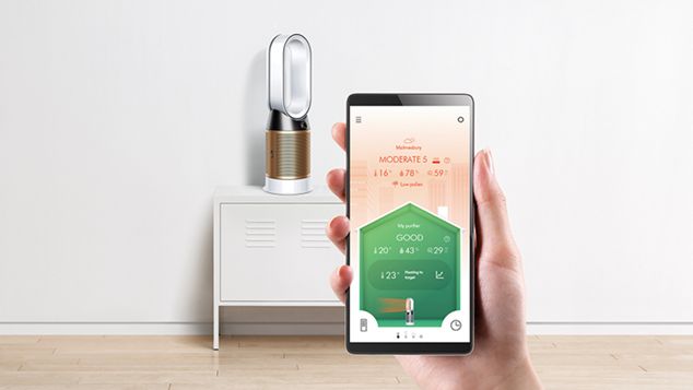 A hand holding up a smart phone in front of a Dyson purifier. The phone screen displays the Dyson Link app.