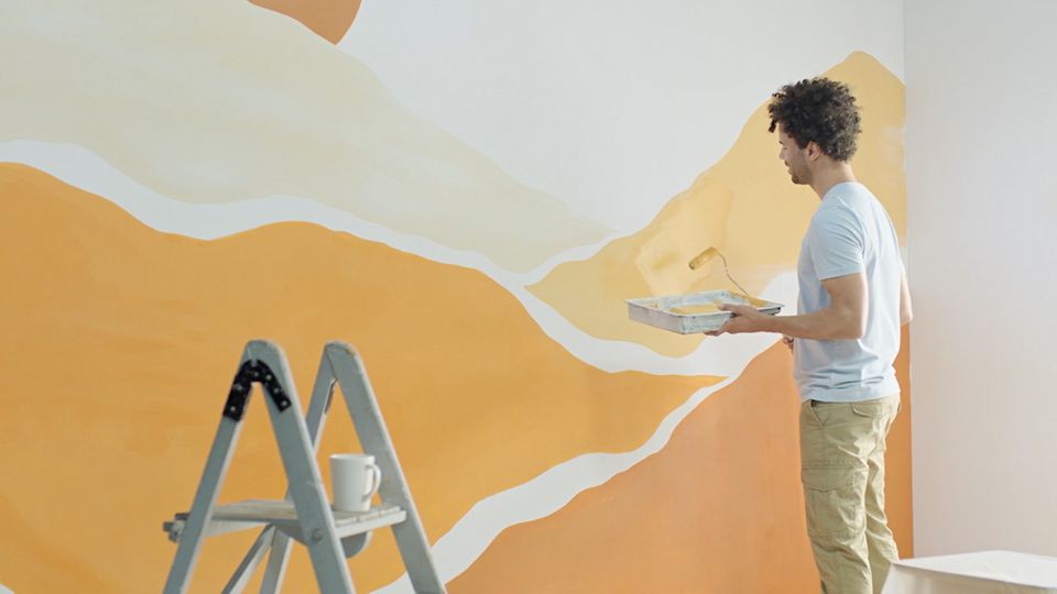 Ein Mann streicht eine innenliegende Wand.