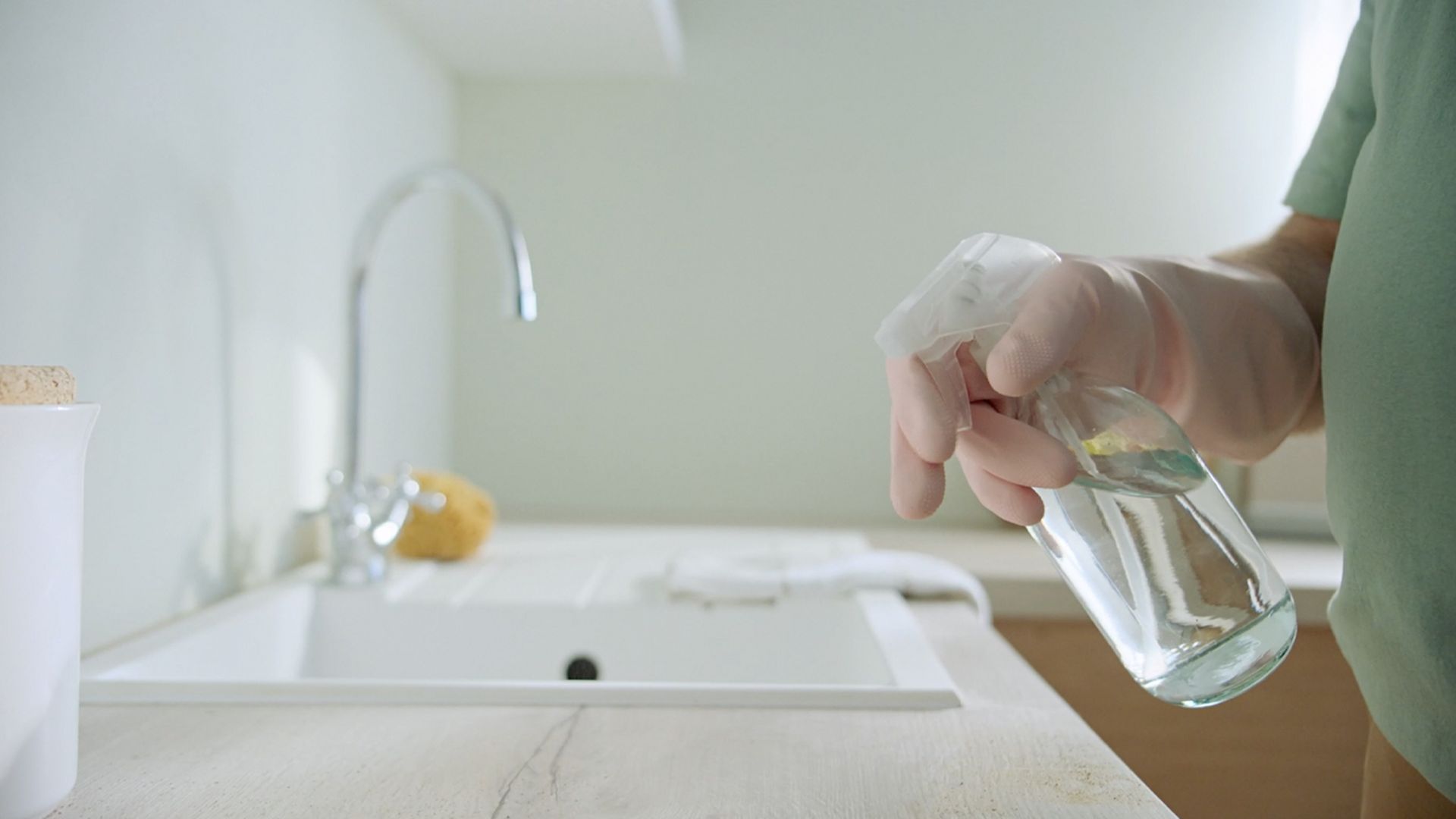 Ein Hand versprüht Desinfektionsspray auf einer Küchenarbeitsfläche. Ein Hand versprüht Desinfektionsspray auf einer Küchenarbeitsfläche.