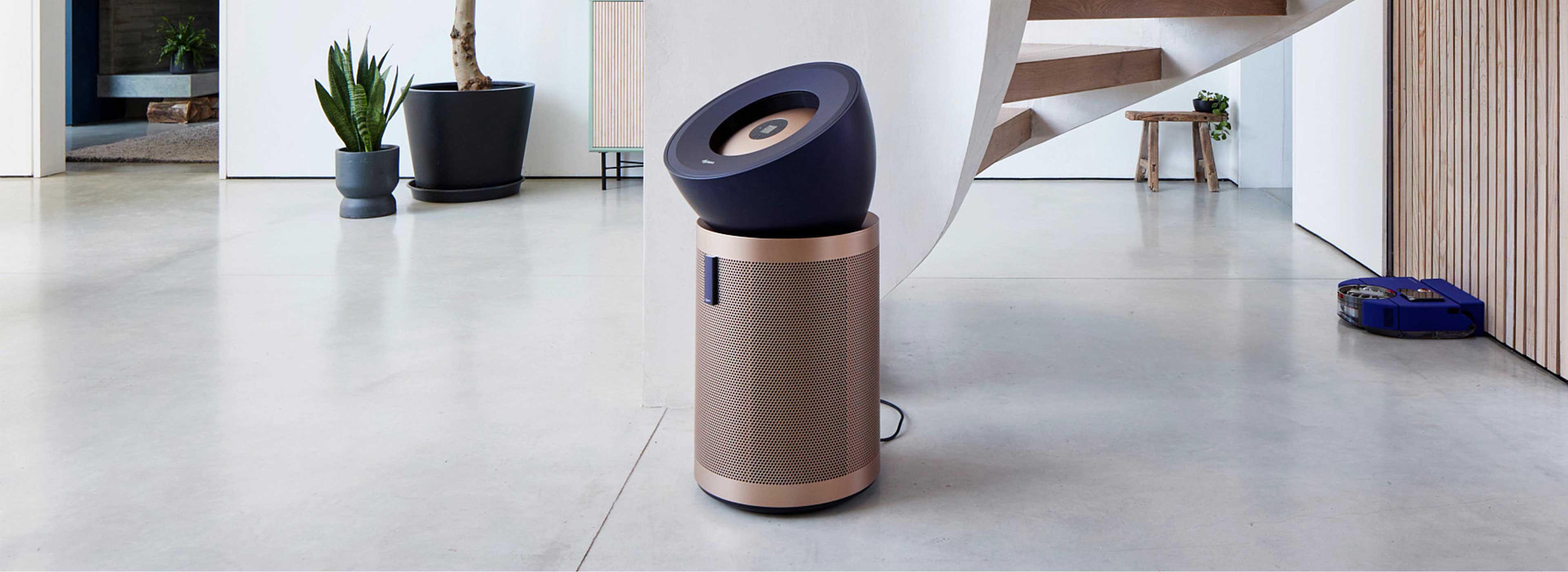 Der Dyson Purifier Big+Quiet Formaldehyde und Dyson Vis Nav Saugroboter in einer modernen Wohnumgebung mit einer Wendeltreppe.
