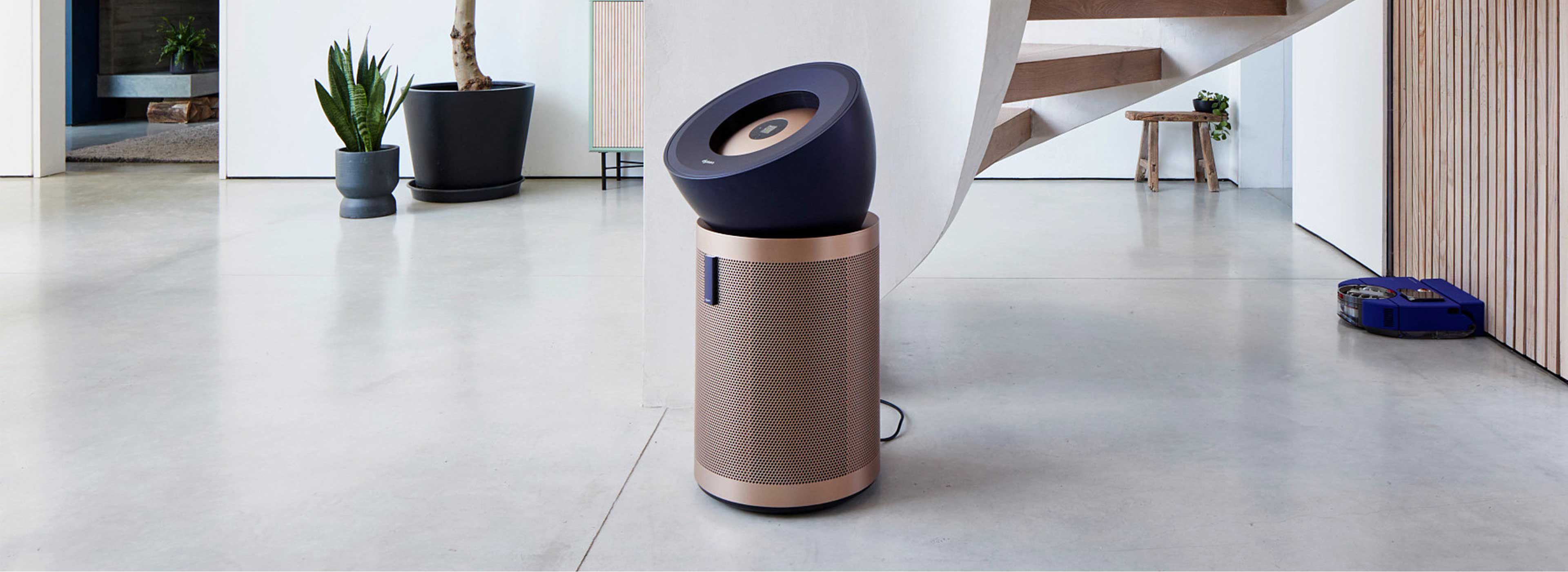 Der Dyson Purifier Big+Quiet Formaldehyde und Dyson Vis Nav Saugroboter in einer modernen Wohnumgebung mit einer Wendeltreppe.