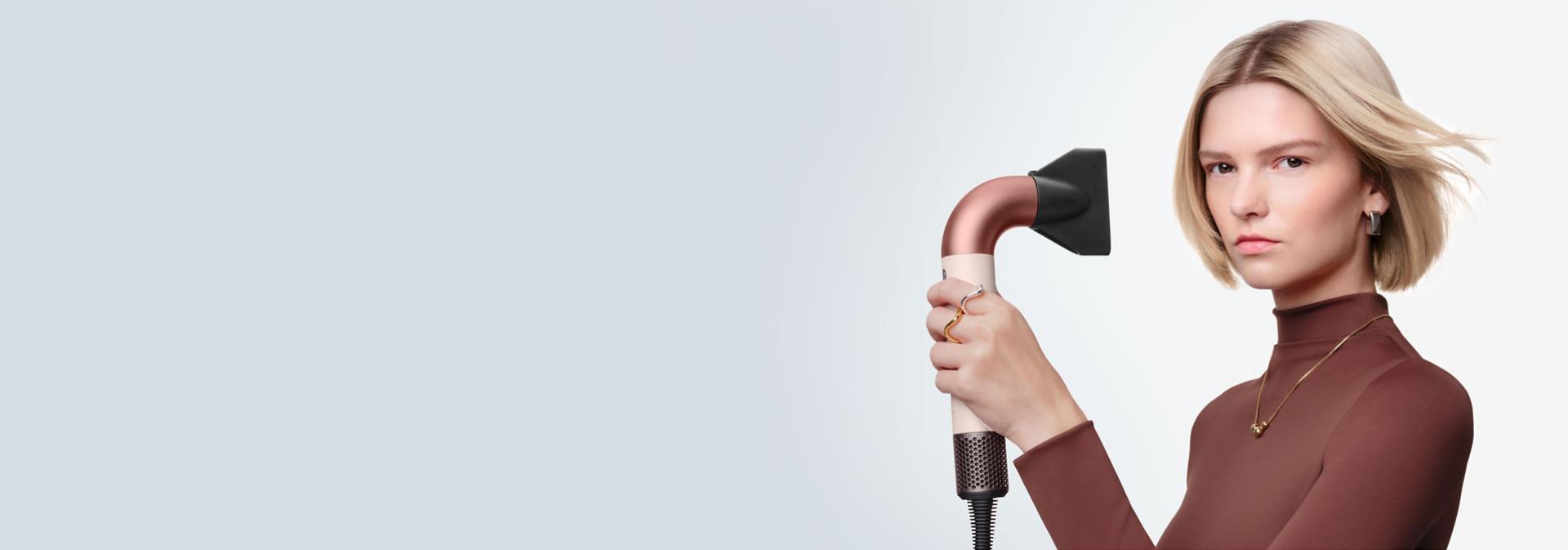 Model dries her hair using the Dyson Supersonic r multi-styler and dryer.