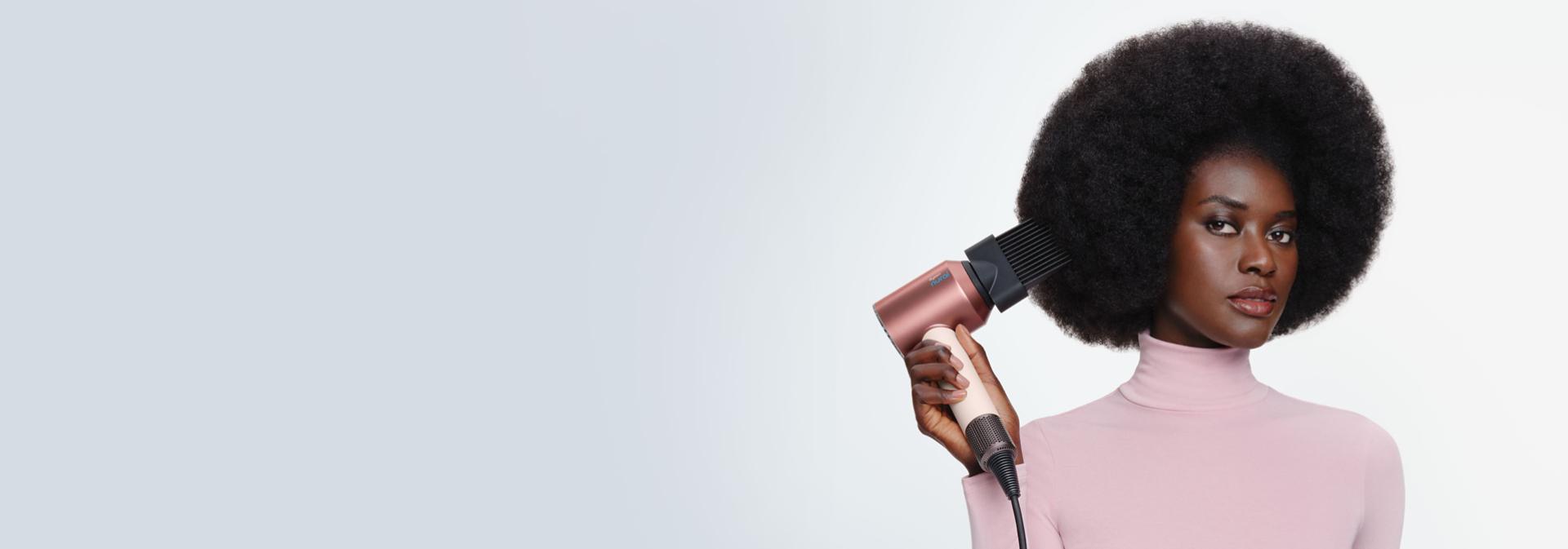 Model curls her hair using the Dyson Airwrap i.d. multi-styler and dryer.
